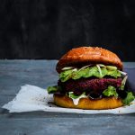 Delicious vegan Red Beet, White Bean &Quinoa Burger with Avocado on a pillowy turmeric brioche bun