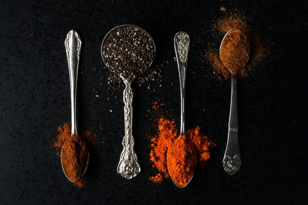 Spoons with spices on a black stone plate
