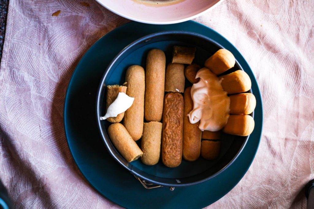 Assembling the Tiramisu cake. 1 row of ladys fingers plus the beginning of the outer wall with upright ladys fingers. Blue plate, pink underground 