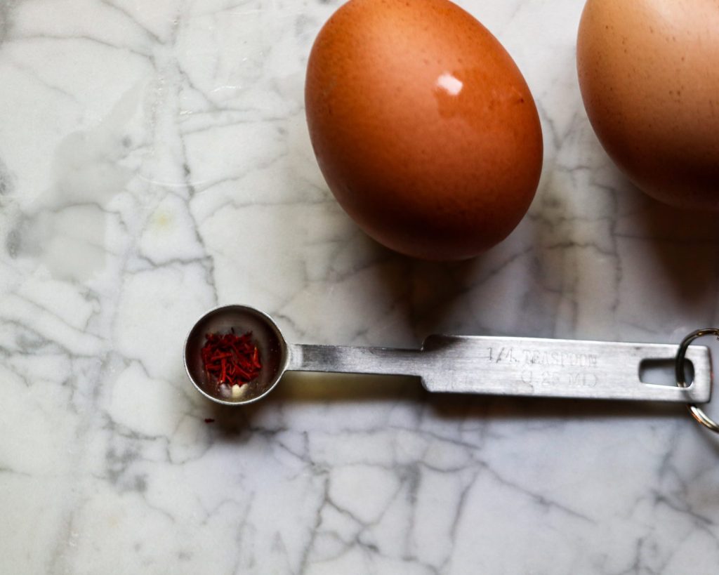 Saffron rice cake ingredients: saffron threads and eggs on a marbled surface