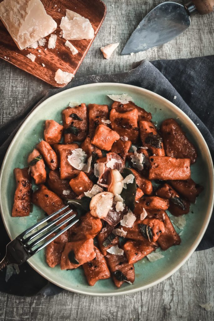 sweet potato pasta in alight blue bowl with fork on the side