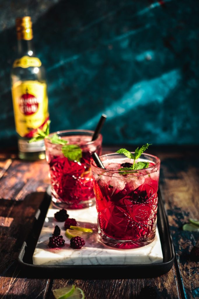 summer nights blackberry-lavender mojitos on a white marbled square with a bottle in the background