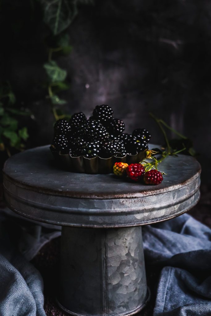 Fresh blackberries in a small tart form on a metallic cake stander